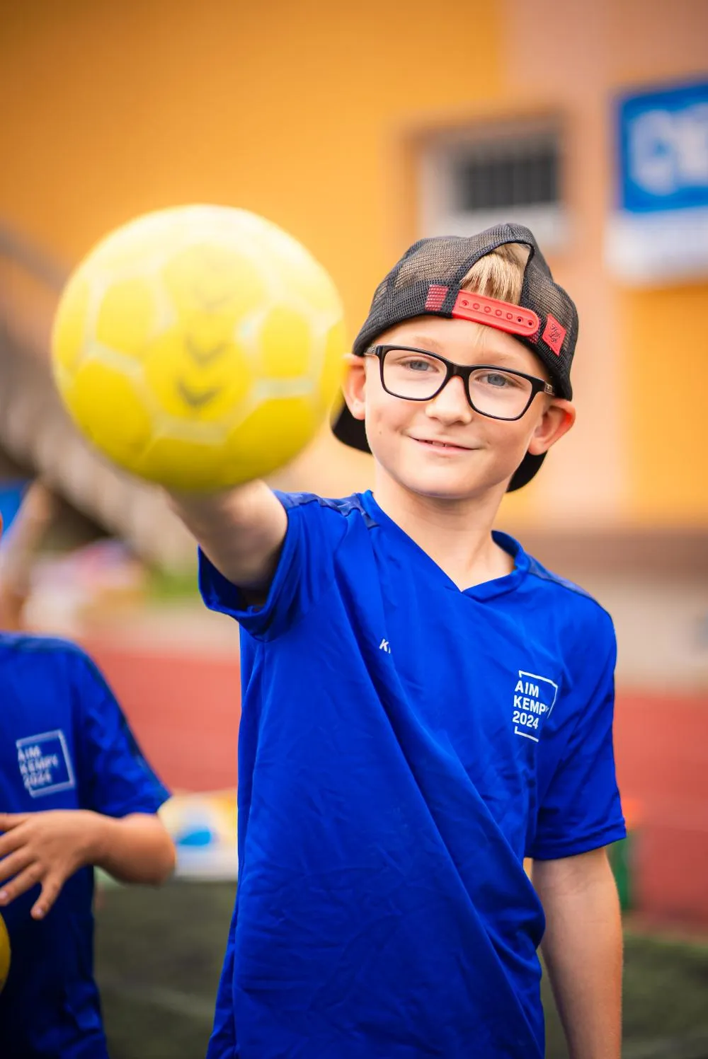 Dva chlapci v modrých tričkách stojí venku a smějí se během sportovní akce.
