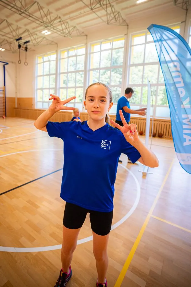 Dva chlapci v modrých tričkách stojí venku a smějí se během sportovní akce.