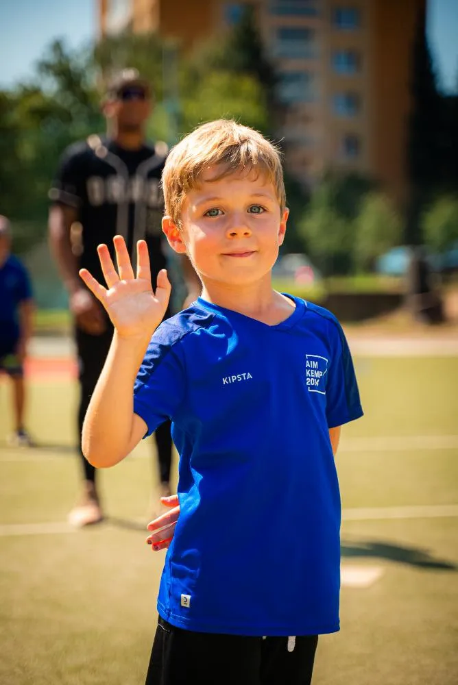 Dva chlapci v modrých tričkách stojí venku a smějí se během sportovní akce.